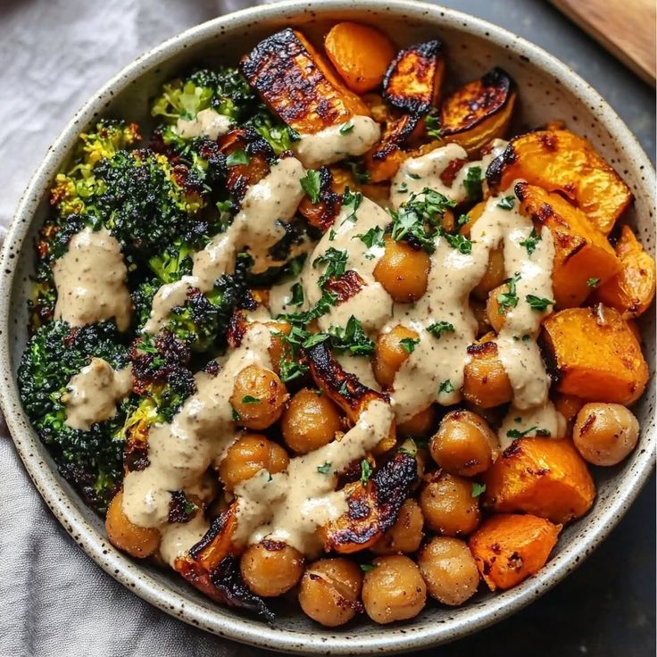 a bowl filled with potatoes, broccoli and some kind of sauce