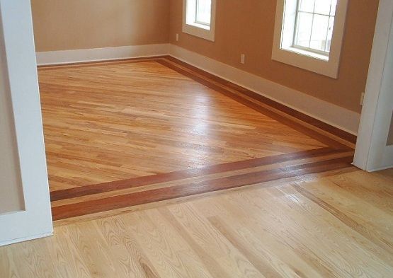 an empty room with hard wood floors and two windows