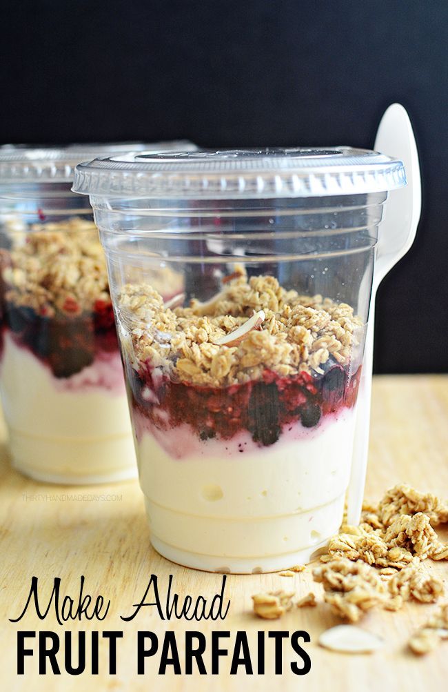 two plastic cups filled with fruit and oatmeal on top of a wooden table