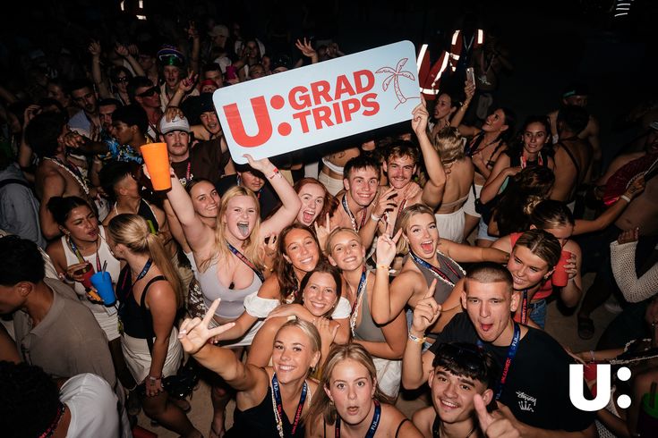 a group of people standing around each other holding up signs that read u - grad trips