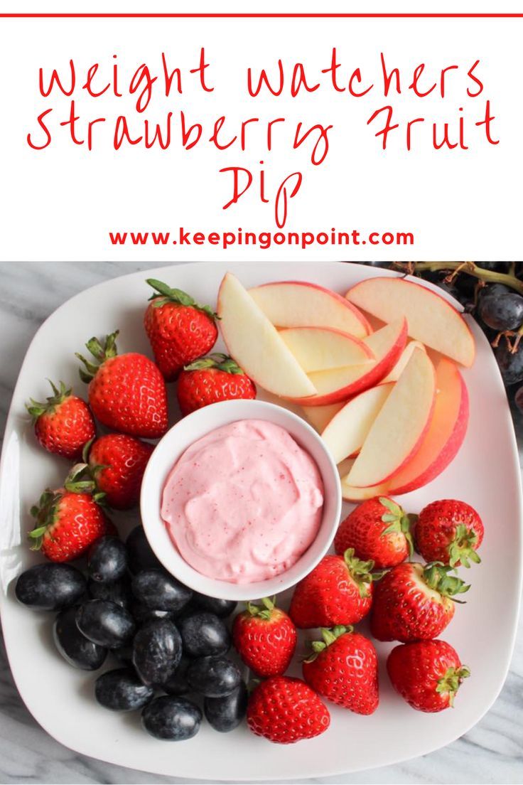 a white plate topped with strawberries and fruit next to a bowl of cream cheese