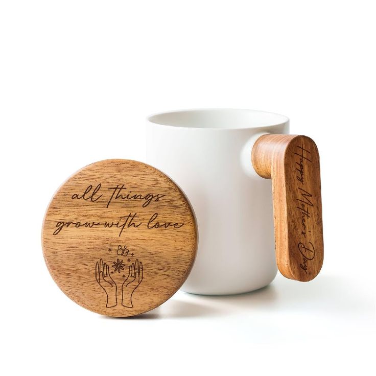 a white mug with two wooden spoons in front of it and an inscription on the cup