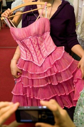 a woman in a pink dress is taking a photo with her cell phone