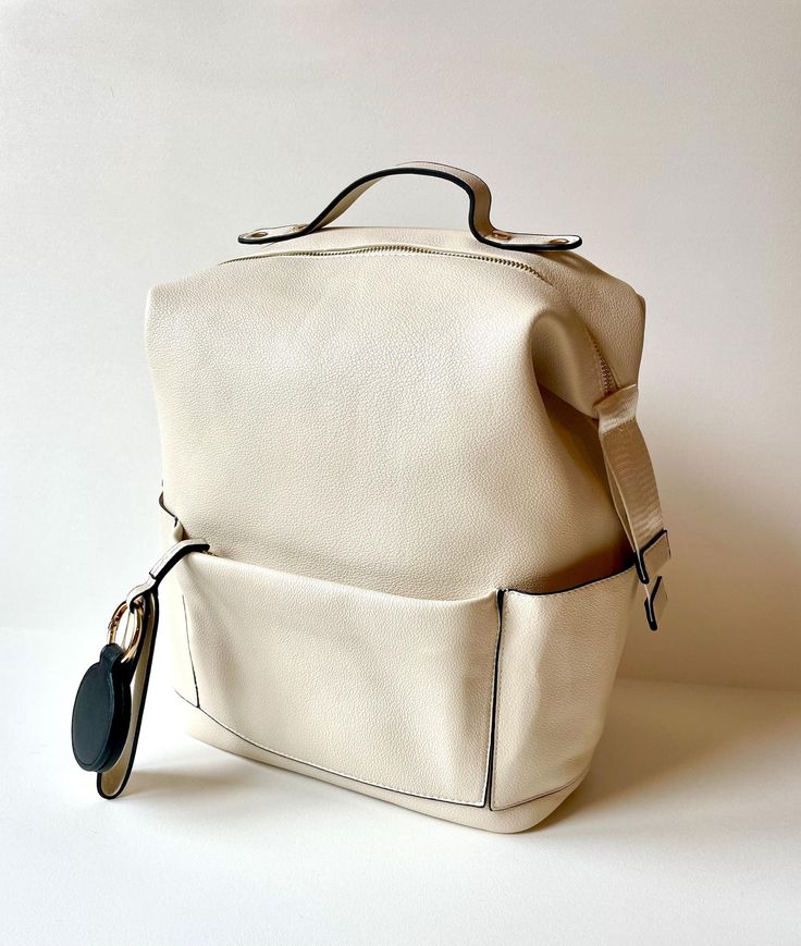 a white bag with a black tag hanging from it's front pocket, on a white background