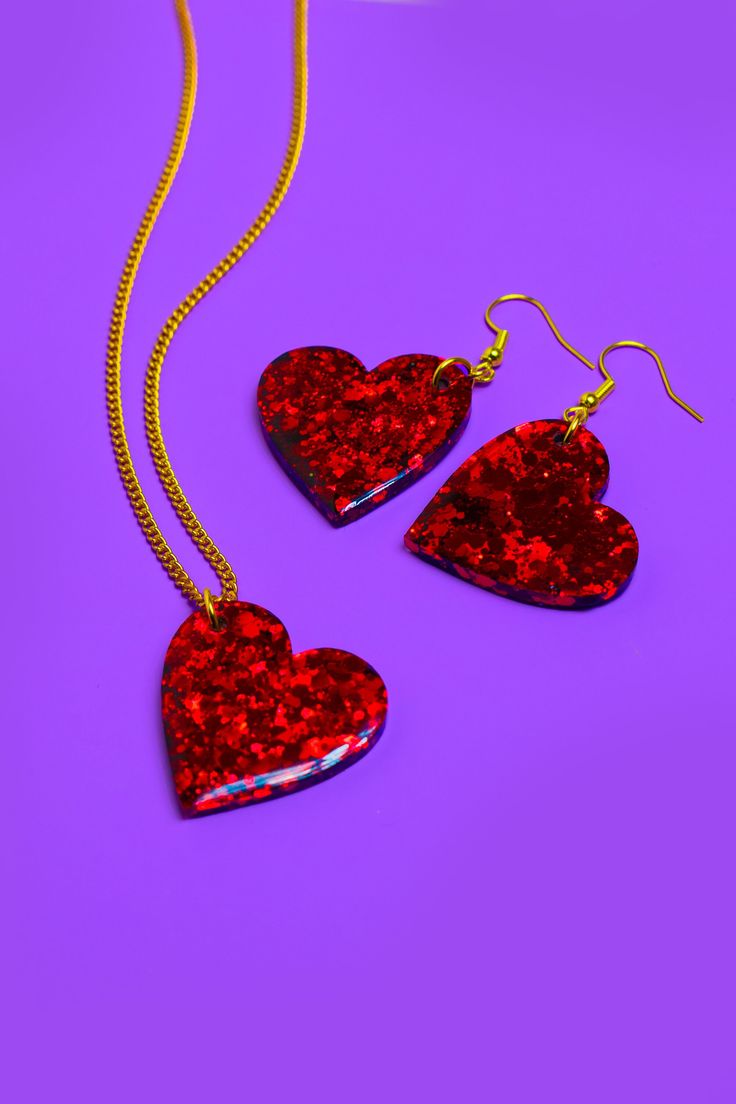 A handmade resin heart shaped necklace and matching earrings, designed to make you look & feel extra. Playful, eye-catching and vibrant, perfect for festivals, parties, special occasions or just to add a touch of sparkle to your everyday look.  Each piece is meticulously crafted with love and attention to detail, ensuring that you receive a unique piece of jewellery that will make you shine.  A combination of high-quality resin and carefully selected glitters creates a mesmerising effect that catches the light and captures attention. ~ RUBY RED SLIPPERS SET ~ Heart dimensions - w2.5 x h2.5cm. Gold plated fish-hook style earrings. Gold plated curb chain approximately 44cm long. Designed and hand crafted from my home studio in Bedfordshire, UK. All jewellery is made to order. Thanks for look Valentine's Day Heart Pendant Necklace For Party, Valentine's Day Heart Charm Necklace For Party, Heart-shaped Party Jewelry, Valentine's Day Heart Beads Party Necklace, Valentine's Day Party Heart Beads Necklace, Double Heart Beads Necklace For Party, Heart Beads Resin Jewelry Gift, Handmade Heart Pendant Necklace For Party, Heart Shaped Resin Jewelry For Valentine's Day