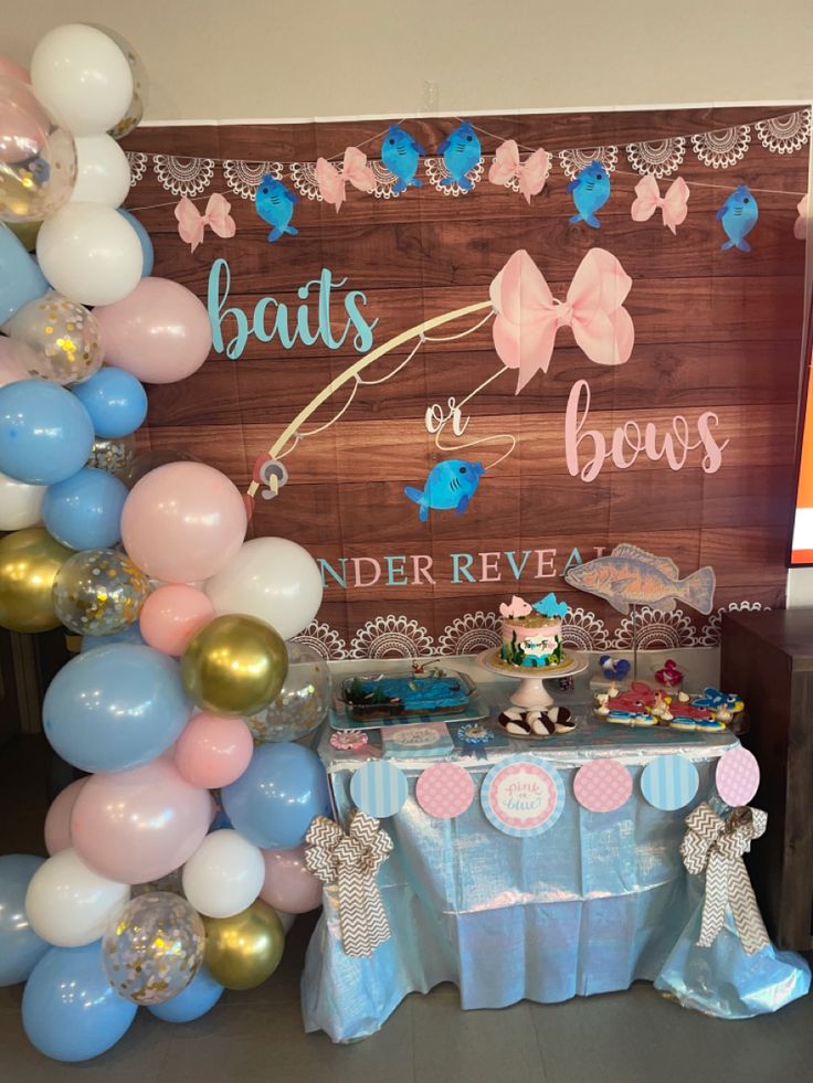 a table with balloons and decorations for a baby's first birthday party in blue, pink and gold