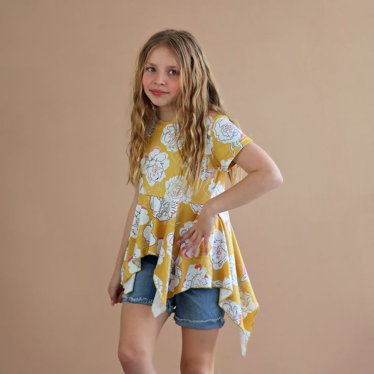 This fun, high-low boho shirt not only is chic in style but a comfy casual fit. 65% Cotton, 35% polyester We recommend hand washing and hang drying this article of clothing. Bohemian Yellow Summer Shirt, Trendy Tops With Curved Hem For Spring, Trendy Spring Tops With Curved Hem, Spring Casual High-low Hem Tops, Casual High-low Hem Blouse For Spring, Casual High-low Hem Blouse For Fall, Cotton Short Sleeve Flowy Tops, Flowy Cotton Short Sleeve Tops, Spring Flowy Short Sleeve Blouse