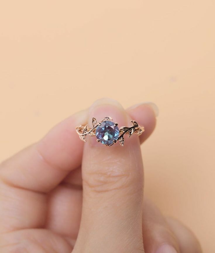 a person holding a ring with a diamond in it's middle and two leaves on the side