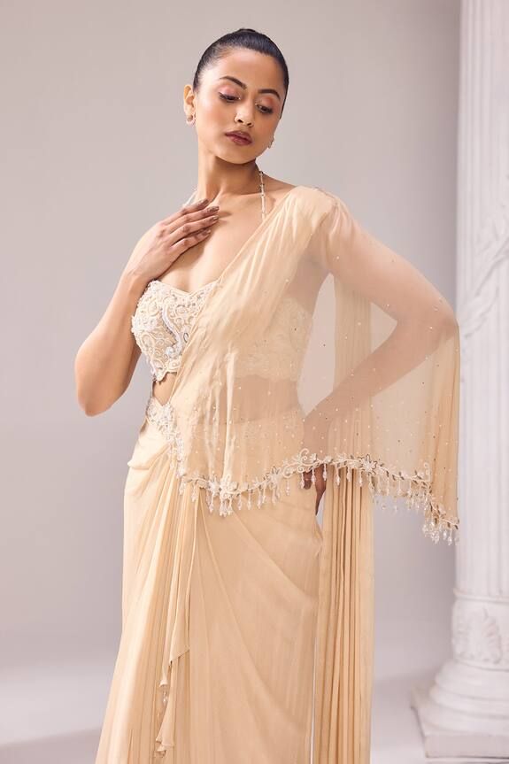 Pale beige asymmetric draped saree with bead, crystal, cutdana embroidery on pallu. Paired with halter neck beaded strap blouse. - Aza Fashions Silk Saree With Pearl Embroidery In Traditional Drape, Designer Cream Pre-draped Saree In Traditional Style, Designer Cream Pre-draped Saree, Designer Pre-draped Cream Saree, Evening Saree With Pearl Embroidery, Beige Pre-draped Saree For Festive Occasion, Elegant Beige Blouse With Traditional Drape, Elegant Beige Blouse Piece With Traditional Drape, Cream Pre-draped Saree For Reception