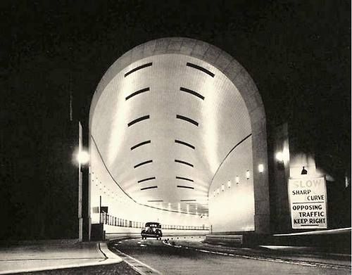 a black and white photo of the inside of a tunnel with cars going through it