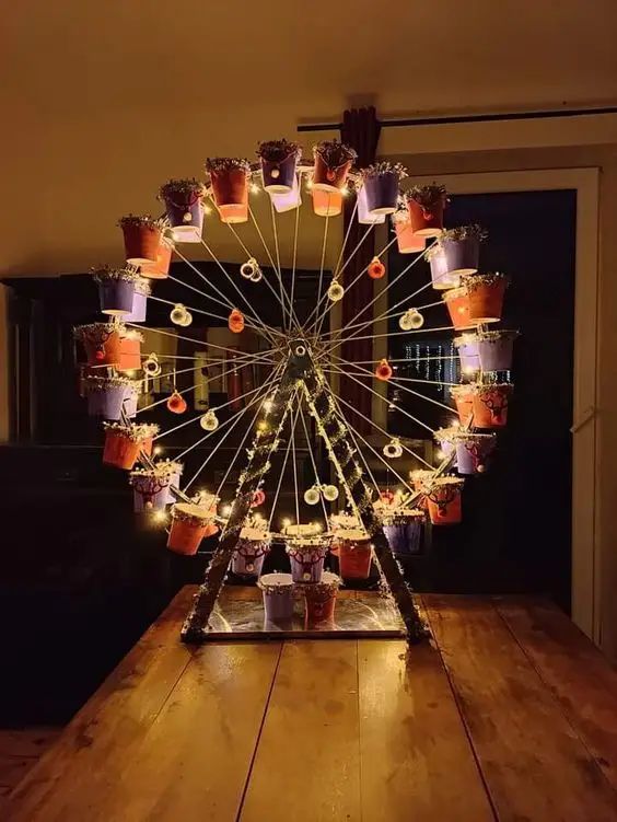 a ferris wheel decorated with potted plants on a wooden table in front of a window