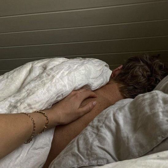 a woman laying in bed with her head on the pillow