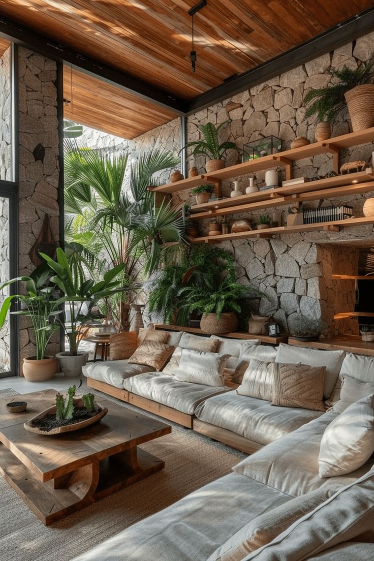 a living room filled with lots of furniture next to a stone wall covered in potted plants