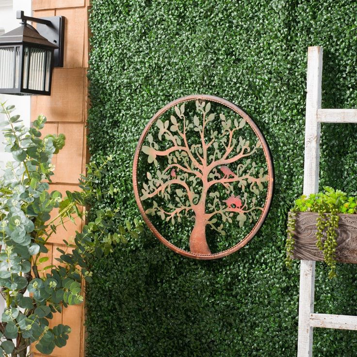 a tree shaped metal wall hanging on the side of a building next to a ladder