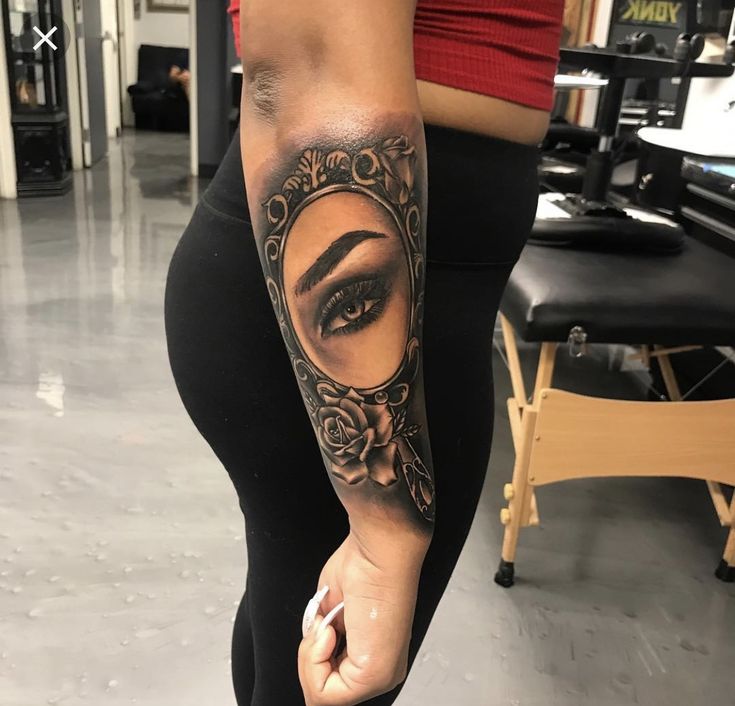 a woman's leg with a tattoo on it and an eye in the mirror