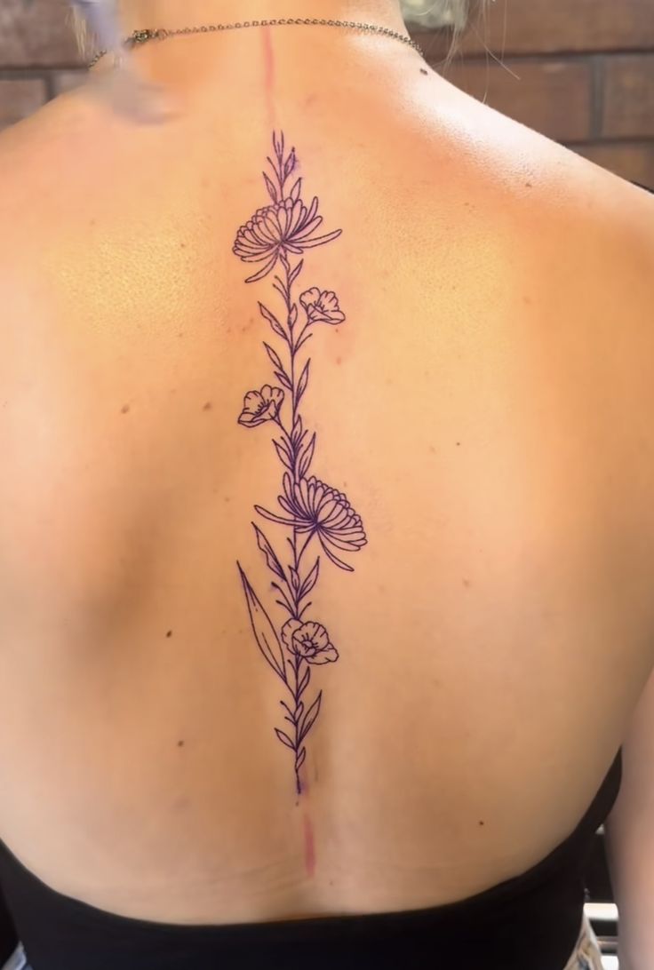 the back of a woman's upper body with flowers on her left shoulder and lower back