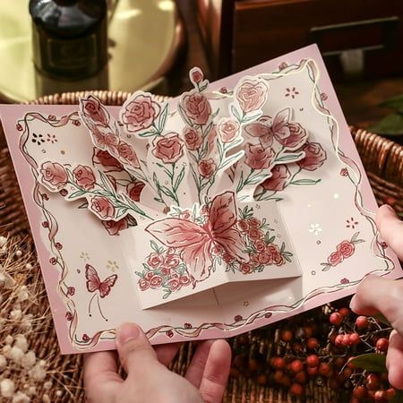 two hands holding an open card with flowers on it