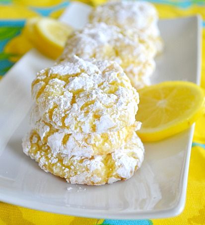 two lemons and some powdered sugar on a white cloth with a slice of lemon in the background