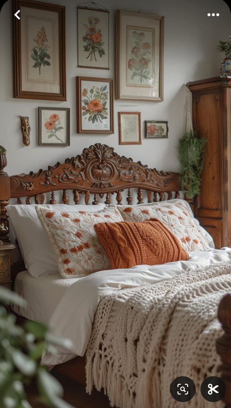 a bed sitting in a bedroom next to pictures on the wall and wooden headboard