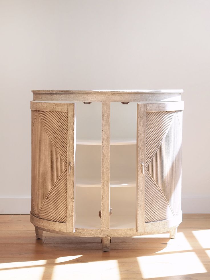 a round wooden cabinet sitting on top of a hard wood floor next to a white wall