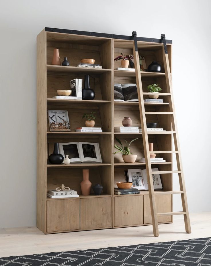 a book shelf with books and vases on it, next to a ladder leaning against the wall