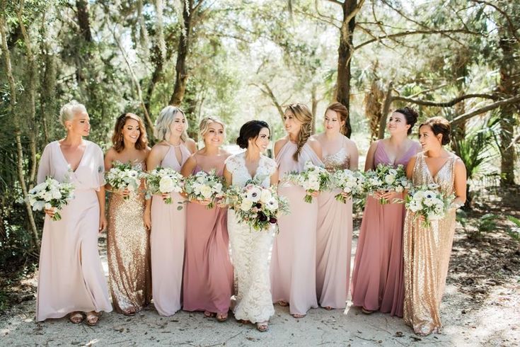 a group of women standing next to each other holding bouquets in their hands and smiling