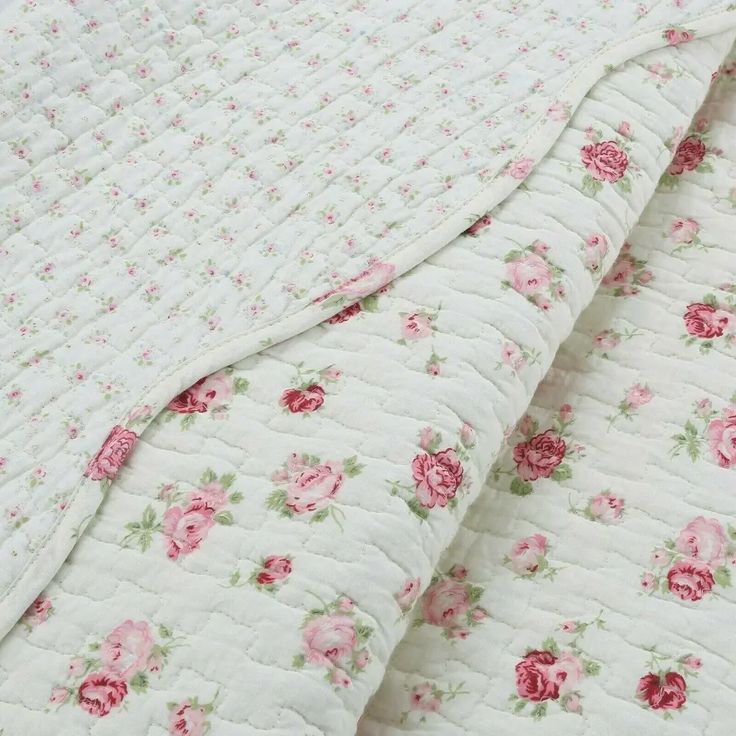 a white quilt with pink flowers on it