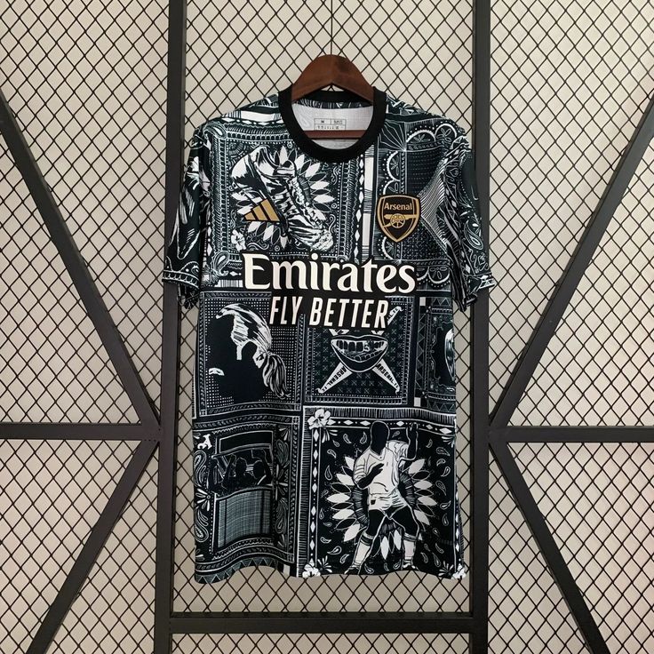 a t - shirt that says emirates fly better hangs on a wall in front of a fence