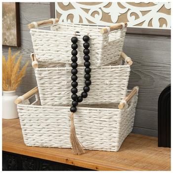 three white baskets stacked on top of each other with black beads and tassels