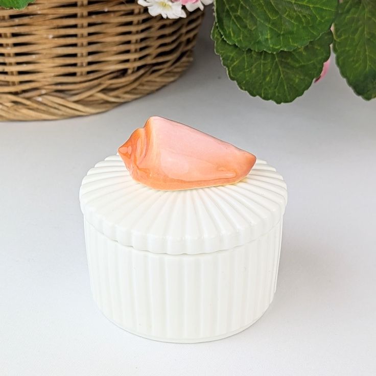 there is a small white container with an orange piece on it next to some flowers