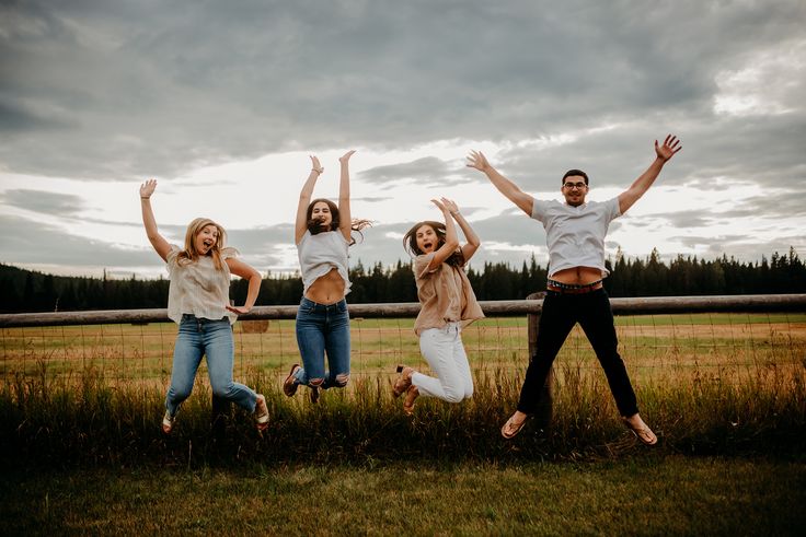 four people jumping in the air with their arms up