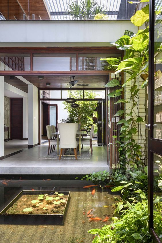 the inside of a house with plants and fish in the water on the patio area