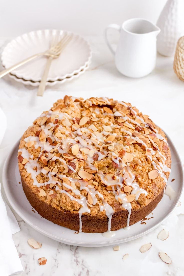 a cake sitting on top of a white plate covered in frosted toppings and nuts