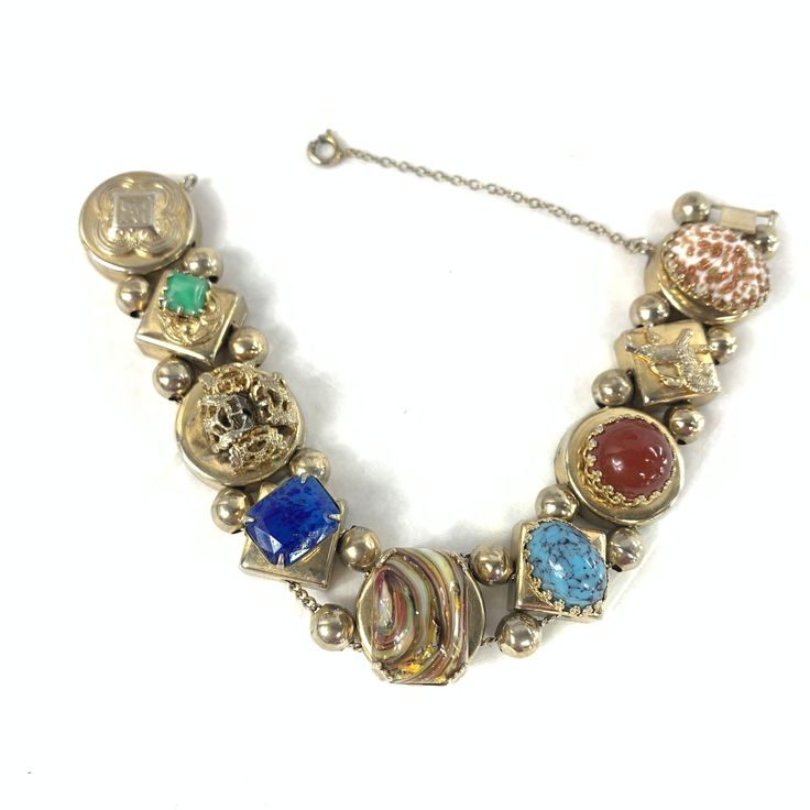 Victorian revival watch chain bracelet, made from reproduction watch and bracelet slides.  The bracelet is unmarked, but it is gold tone with high quality glass gems. It includes lapis style, Peking jade glass, Hubbell glass, and two gorgeous Italian Murano style and aventurine gems, plus a roaring lion and a bow. It's gorgeous and impressive, and this particular size and quality is VERY hard to find.  From the 1950's. I believe. Some wear, as expected, but in beautiful shape. Stones are not cho Vintage Yellow Gold Cabochon Bracelets, Antique Jeweled Metal Jewelry, Heirloom Gold Multi-stone Bracelets, Heirloom Gold Bracelets With Multi-stone, Antique Jeweled Silver Jewelry, Antique Silver Jeweled Jewelry, Collectible Jeweled Bracelet, Antique Jeweled Jewelry, Collectible Jewels Bracelet