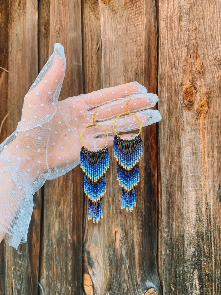 "🌊🌞 Dive into summertime with these stunning Blue Gold Ombre Beaded Fringe Earrings! These handwoven American style earrings are inspired by the vibrant colors of the ocean and make the perfect gift for any beach lover. Crafted from high-quality seed beads, these earrings feature a beautiful ombre design that fades from blue to gold, a symbol of the shining sun reflecting off the ocean.  These Blue Gold Ombre Beaded Fringe Earrings are perfect for adding a pop of color to any outfit. Their unique design will set you apart from any crowd. Whether you're heading to the beach or to a summer party, these earrings are the perfect accessory to complete your look. So why wait? Order your Blue Gold Ombre Beaded Fringe Earrings today and add a touch of ocean-inspired beauty to your style!🌊 🔎Siz Handwoven Gold Jewelry For Summer, Blue Handwoven Dangle Jewelry, Handwoven Dangle Earrings For Summer, Handmade Beach Drop Chandelier Earrings, Handmade Beach Chandelier Drop Earrings, Beaded Fringe Dangle Jewelry For Beach, Beach Dangle Jewelry With Beaded Fringe, Blue Beaded Fringe Jewelry For Beach, Handwoven Dangle Jewelry For Beach