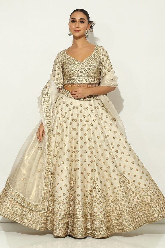 Ivory and gold kalidar lehenga with all over Padma bagh motif embroidery using zardozi highlights and tassel ornamentation. Paired with an elbow sleeves floral jaal embroidered leaf neck blouse with dangling glass beads hem and a bloom border embroidered dupatta. - Aza Fashions Beige Set With Intricate Embroidery And Traditional Drape, Beige Embroidered Reception Set, Cream Sets With Resham Embroidery For Reception, Cream Embroidered Sets With Traditional Drape, Elegant Beige Choli With Intricate Embroidery, Elegant Embroidered Cream Lehenga, Elegant Cream Choli For Festive Occasions, Elegant Cream Choli For Festive Season, White Raw Silk Lehenga For Reception