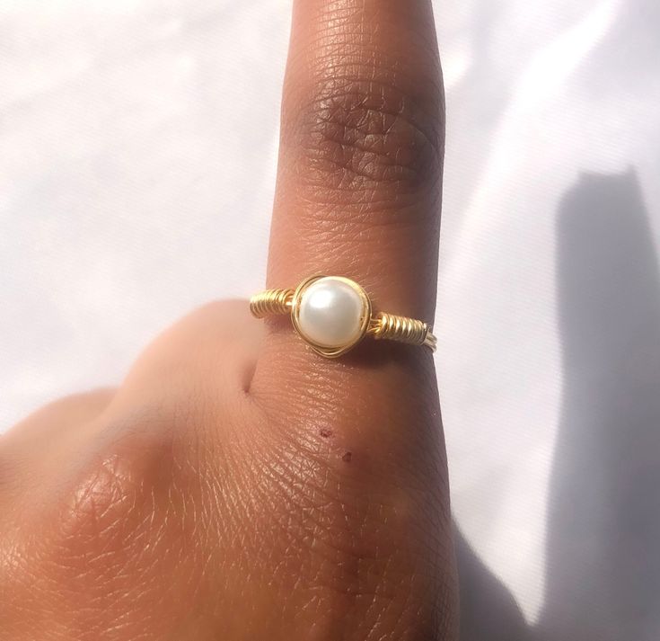 This simple gold, dainty, faux pearl ring is handmade out of wire, this ring is sturdy but can be bent, so a lot of force should not be applied to this! You only get 1 ring per purchase. I also sell matching pearl earrings, a simple pearl necklace and bridal pearl necklaces, these are all perfect to wear throughout the summer.  SIZING: - US 4 --- UK H--- Pandora size 46 --- 14.60mm (diameter) - US 4 1/2 --- UK H1/2 - I1/2 --- Pandora size 48 --- 15.30mm  - US 5 --- UK J-K --- Pandora size 50 --- 16.00 mm - US 5 1/2 --- UK K-L --- Pandora size 51 - 16.2 mm - US 6 --- UK L - L1/2 --- Pandora size 52 ---16.50mm - US 6 1/2 --- UK M --- Pandora size 53 --- 16.9mm - US 7 --- UK N --- Pandora size 54 --- 17.20mm - US 7 1/2 --- UK O - P --- Pandora size 56 --- 17.80mm - US 8 --- UK P --- Pandora s Dainty Toe Ring Jewelry With Simple Design, Hypoallergenic Dainty Ring Jewelry, Handmade Minimalist 14k Gold Filled Ring, Minimalist Wire Wrapped Open Ring Jewelry, Dainty 14k Gold Filled Toe Ring, Dainty Gold Toe Ring, Handmade 14k Gold Filled Rings, Handmade Delicate 14k Gold Filled Rings, Dainty Handmade Midi Rings For Promise