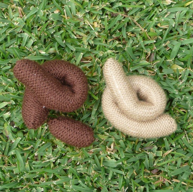 two knitted teddy bears laying in the grass