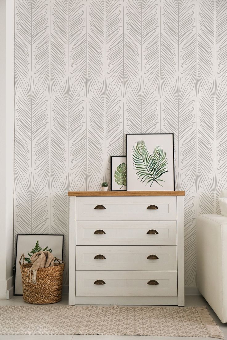 a white dresser sitting in front of a wall with a plant on top of it