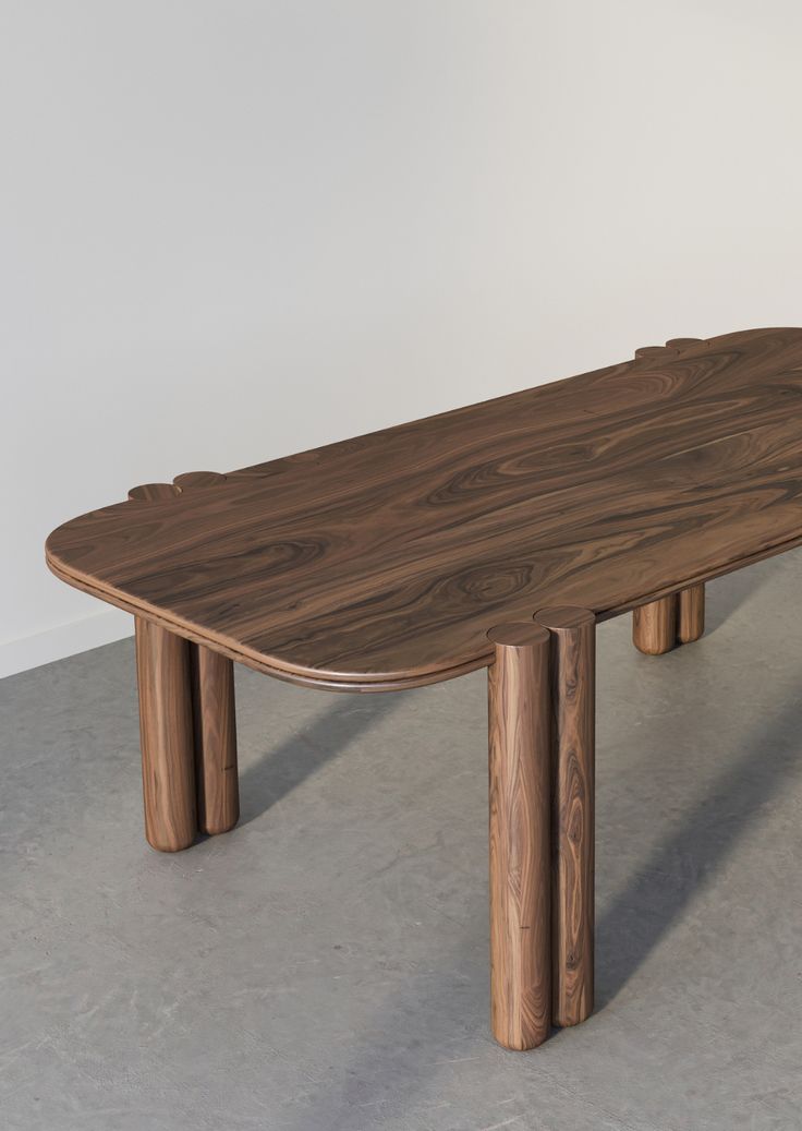 a wooden table sitting on top of a cement floor next to a white walled wall