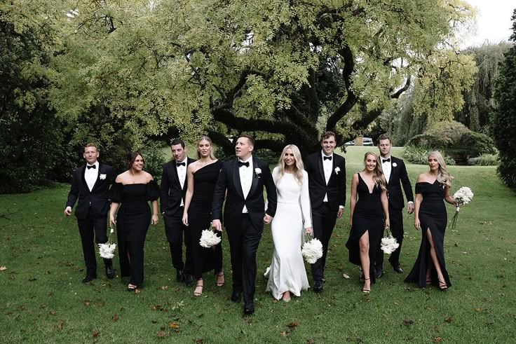 a group of people standing next to each other in front of a tree and grass field