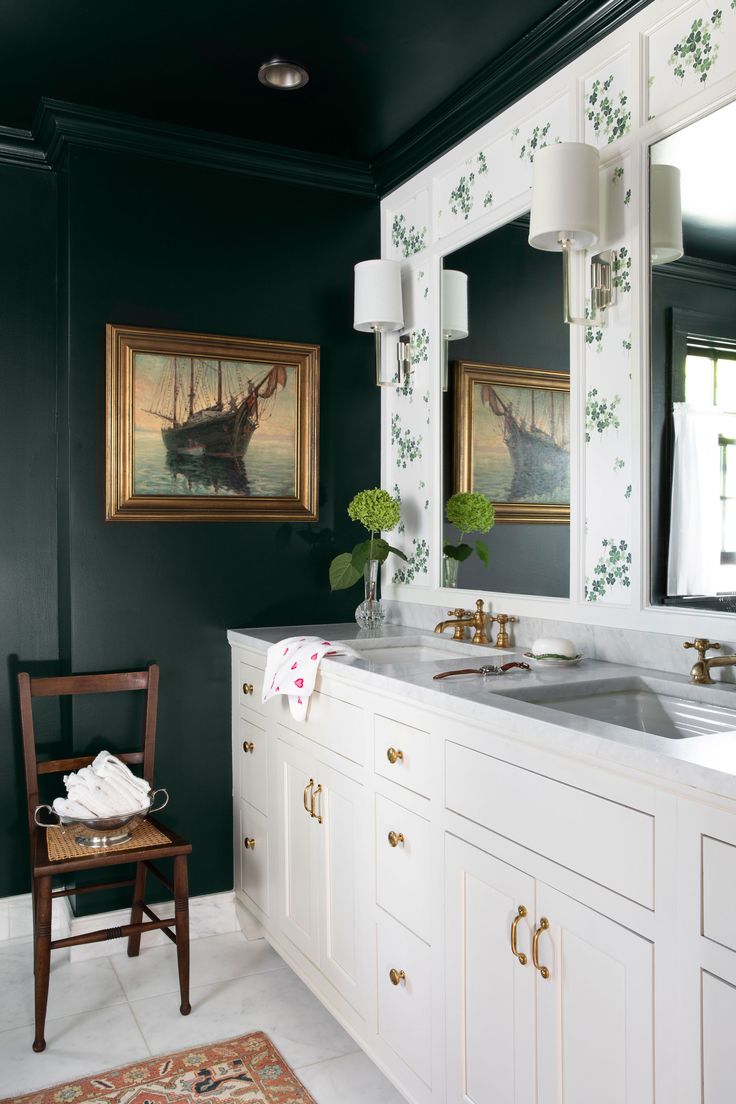 a bathroom with green walls and white cabinetry is pictured in this image, there are two paintings on the wall