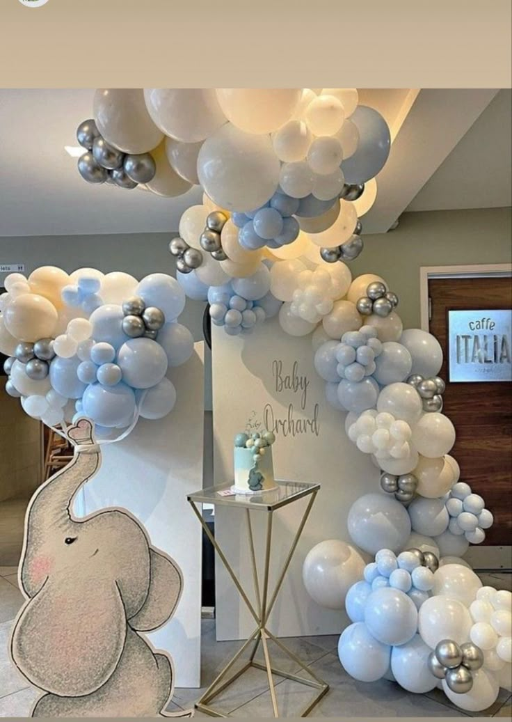 an elephant balloon arch is decorated with blue and white balloons for a baby's first birthday