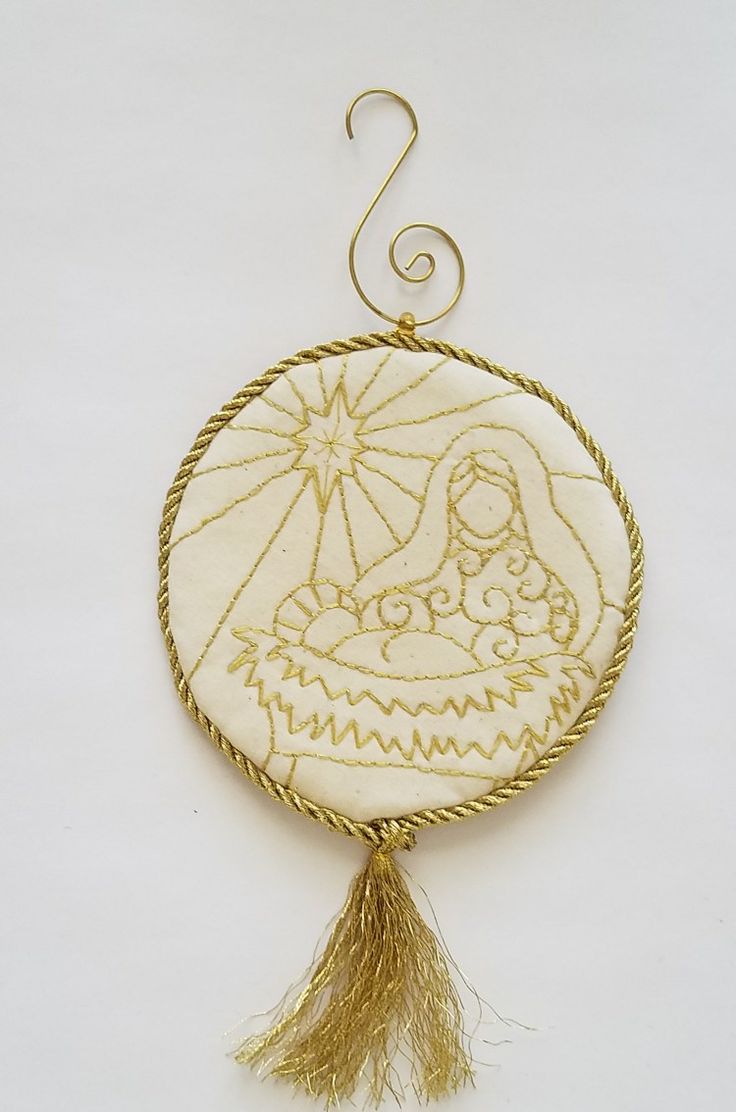 an embroidered ornament hanging from a wire on a white background with a gold tassel