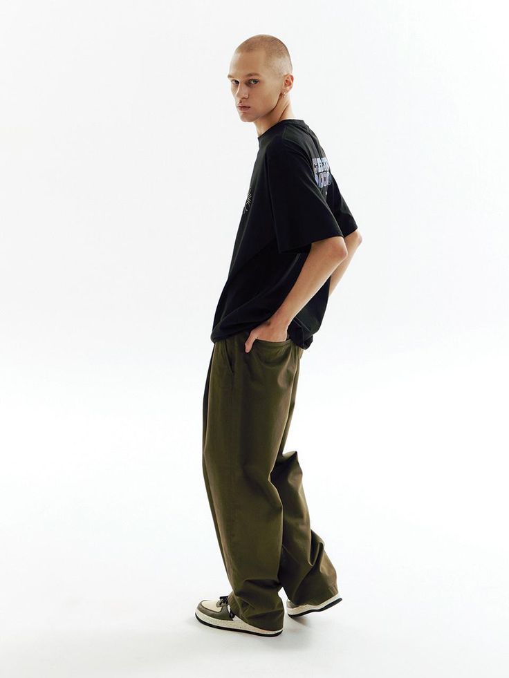 a man in black shirt and khaki pants standing with his hands on his hips