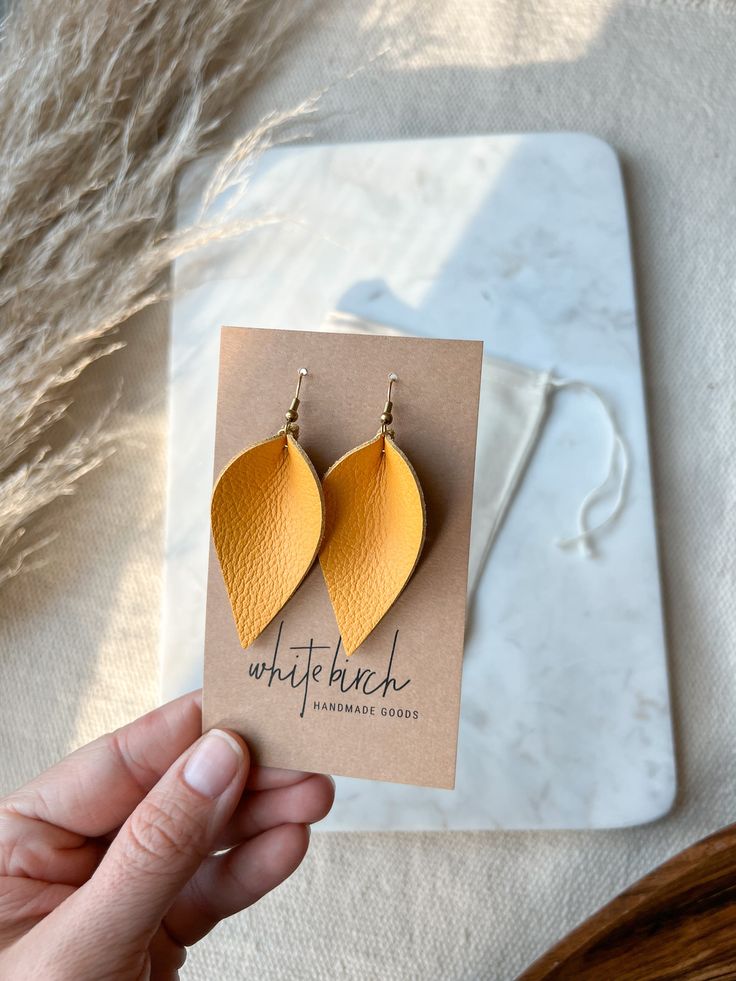 Ready for summer? Just add these yellow statement earrings! •••••••••••••••••••••••••••••••••••••••••••••••••••••••••••••• • ORDERING • These leather leaf earrings are available in 2 sizes: • Small Leaf measures approx 2" or 2 1/2" with hook. • Large Leaf measures approx 3" or 3 1/2" with hook. The dangle earrings have hypo-allergenic ear wires. Nickel and lead free. Choose one of our finishes of ear wire from the drop down. Available finishes are:• Raw Brass Hooks• Stamped .925 Sterling Silver Trendy Handmade Earrings For Everyday Use, Minimalist Orange Earrings For Everyday, Orange Minimalist Earrings For Everyday, Elegant Yellow Earrings For Summer, Summer Single Yellow Earring, Everyday Minimalist Orange Earrings, Elegant Yellow Summer Earrings, Yellow Earrings For Summer Gifts, Orange Earrings For Everyday Summer Wear