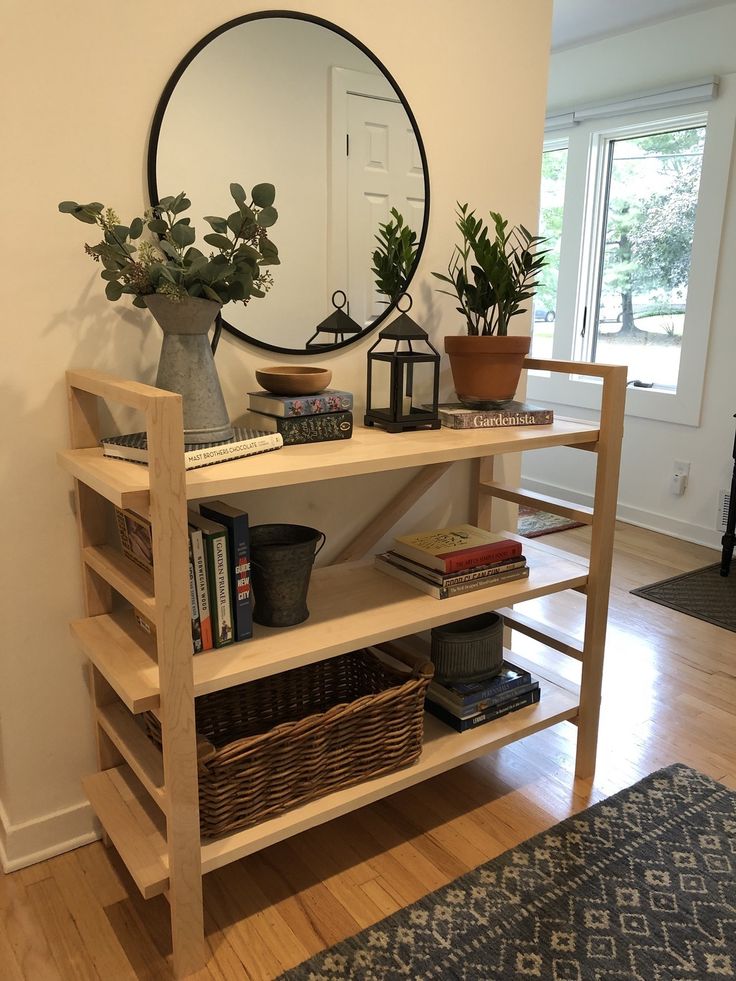 a shelf with books and plants on it in front of a large round mirror over a doorway