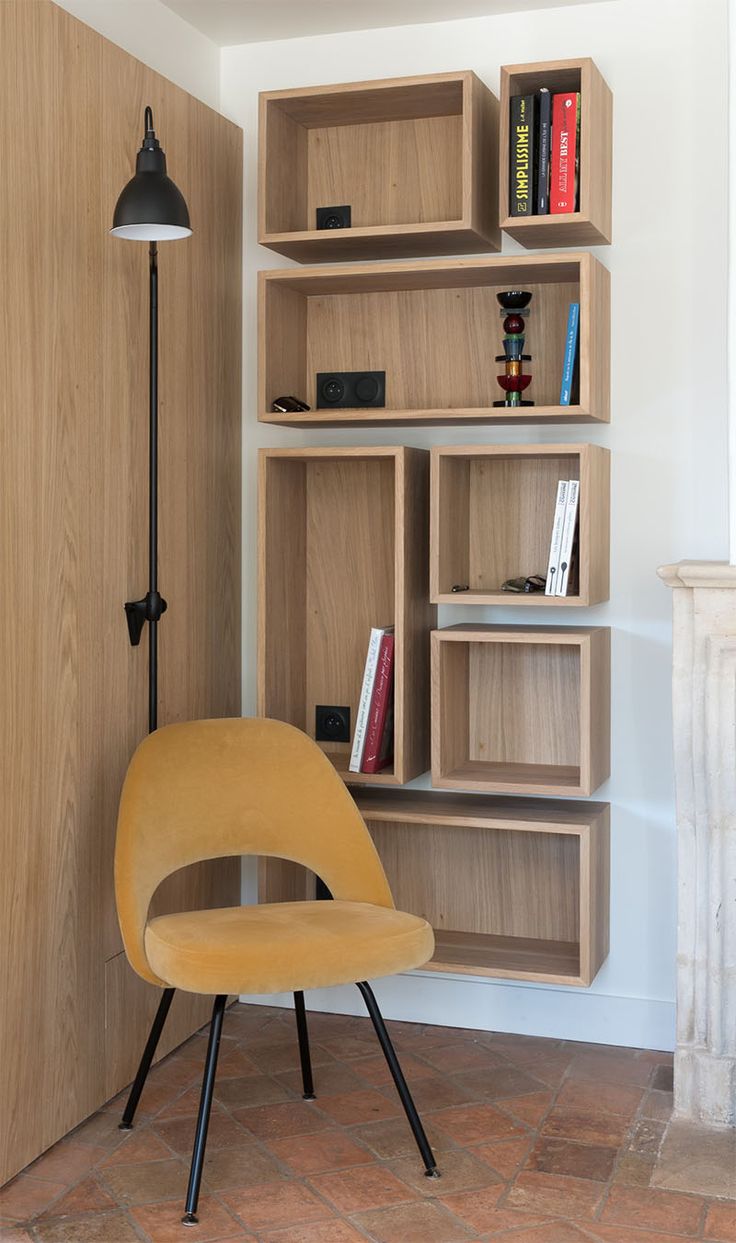 a yellow chair sitting in front of a wooden book shelf with books on it's sides