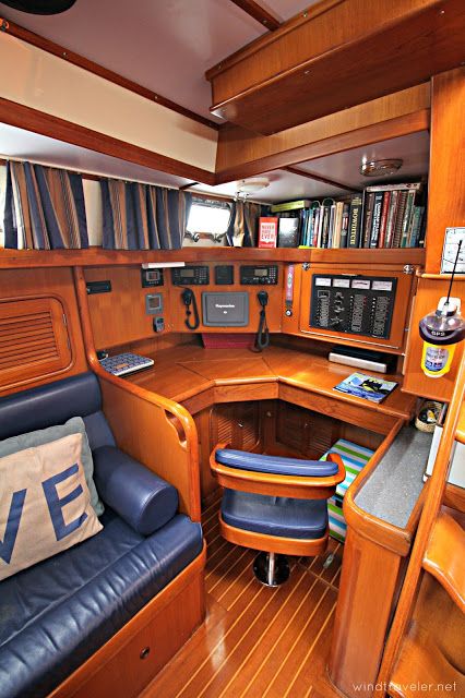 the inside of a boat with lots of books on shelves and blue leather chairs in front of it