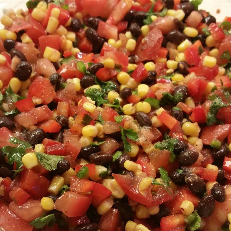 a salad with black beans, corn and cilantro in it on a white plate